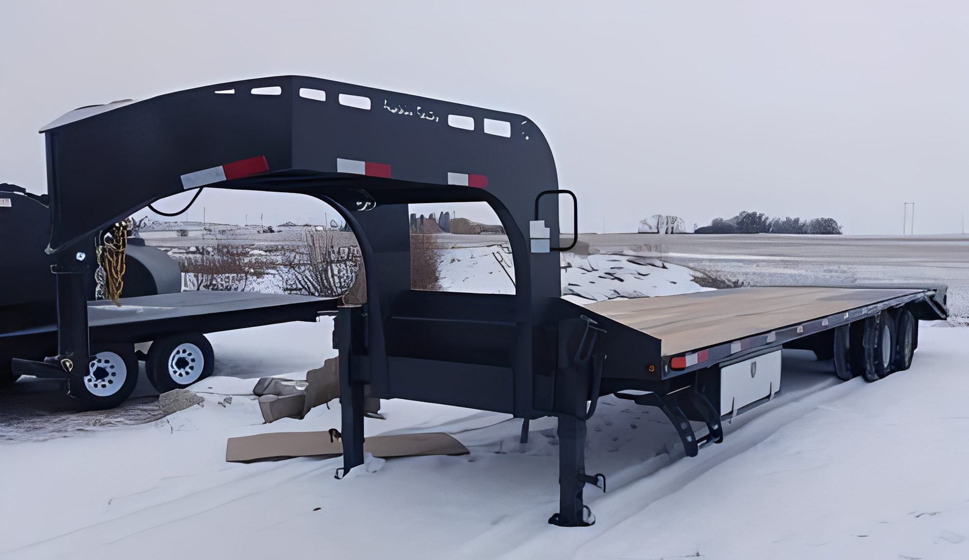 Black flatbed trailer parked in winter
