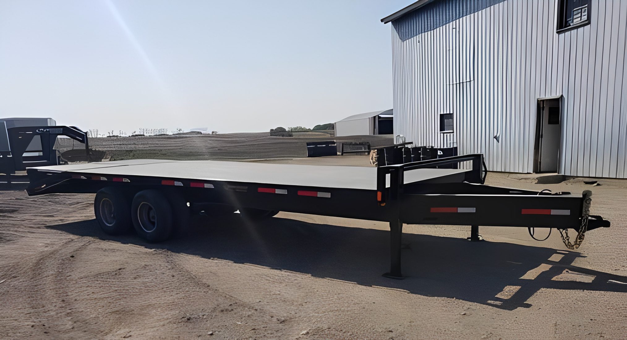 Metal flatbed trailer near industrial building.